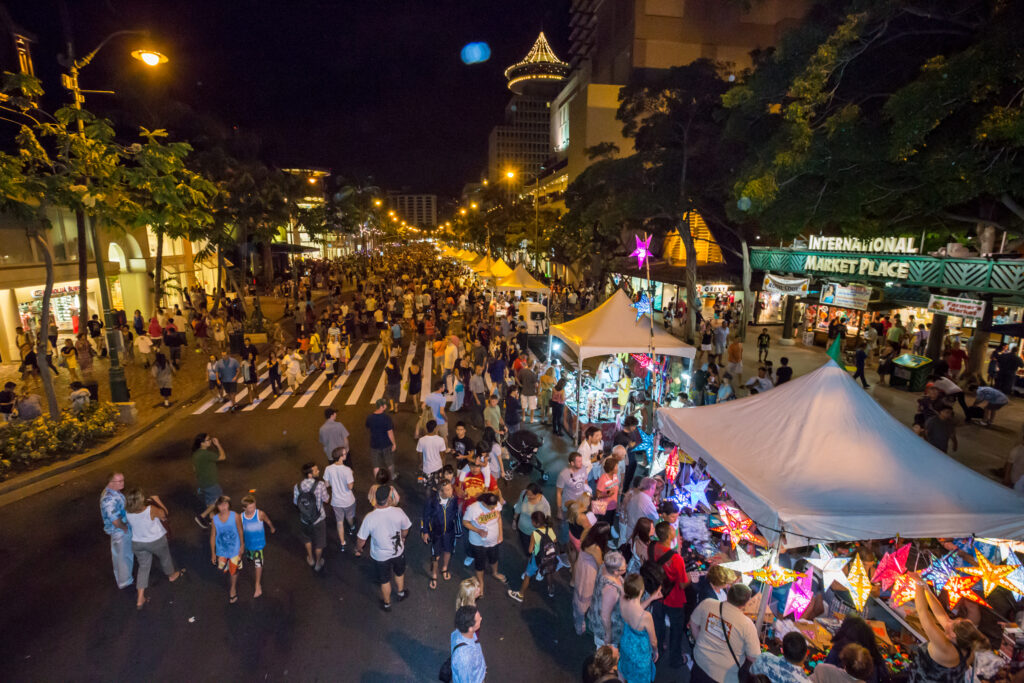 A street festival with lots of people and vendors at night