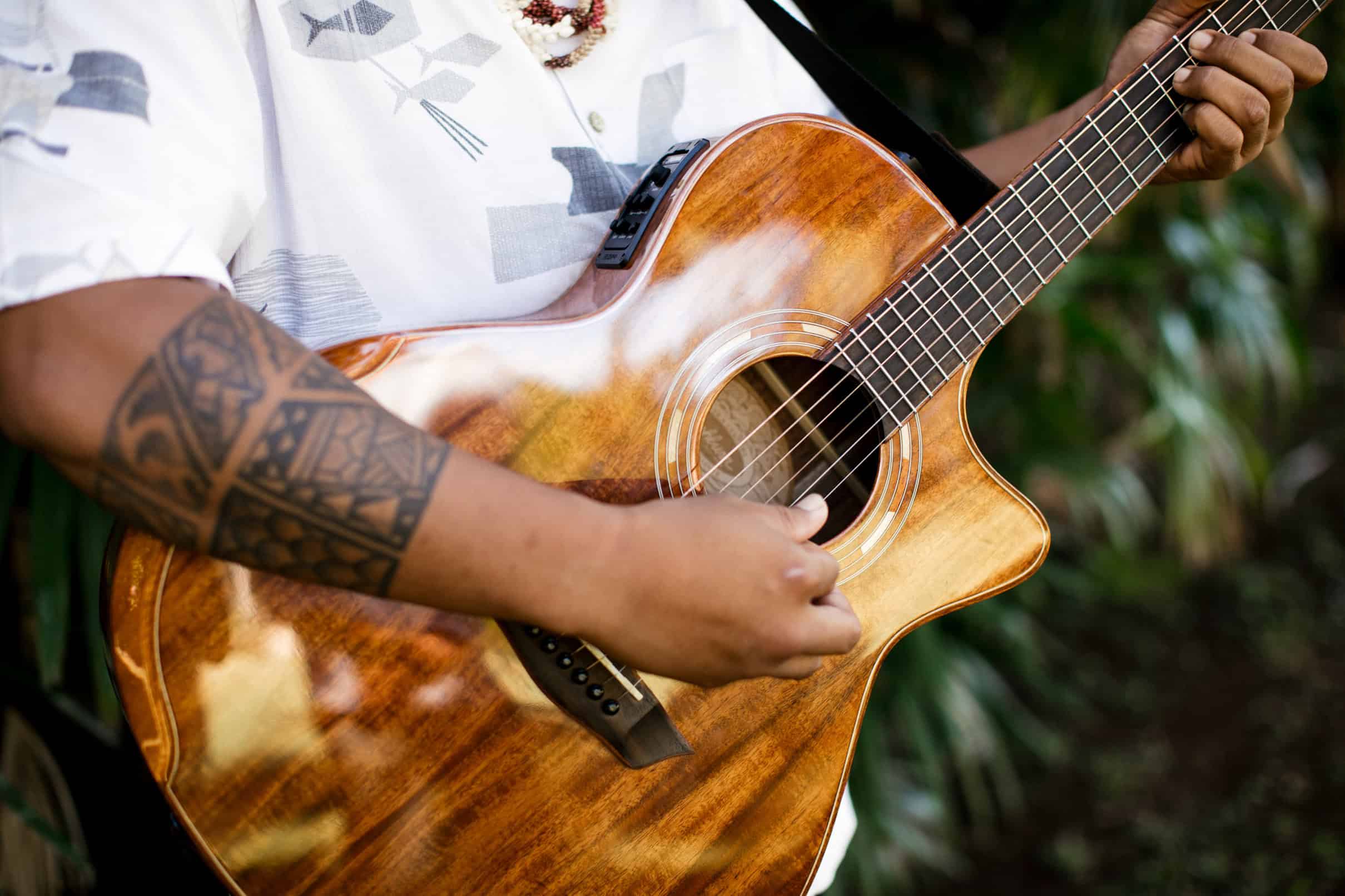 A man with tattoos on his arm playing a guitar