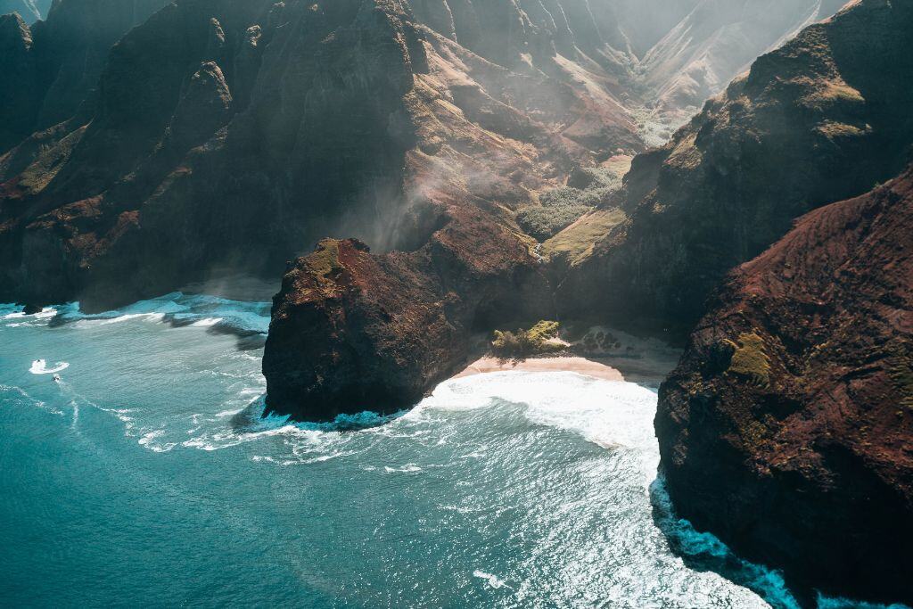 An overhead view of the Na Pali Coast in Kauai, looking down at cliffs and a beach with turquoise water