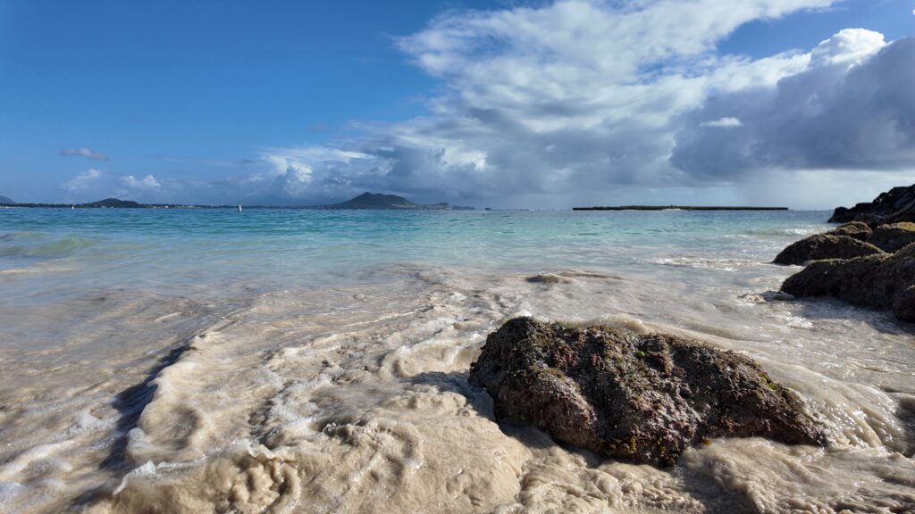 A beautiful beach with calm turquoise water and islands in the background.
