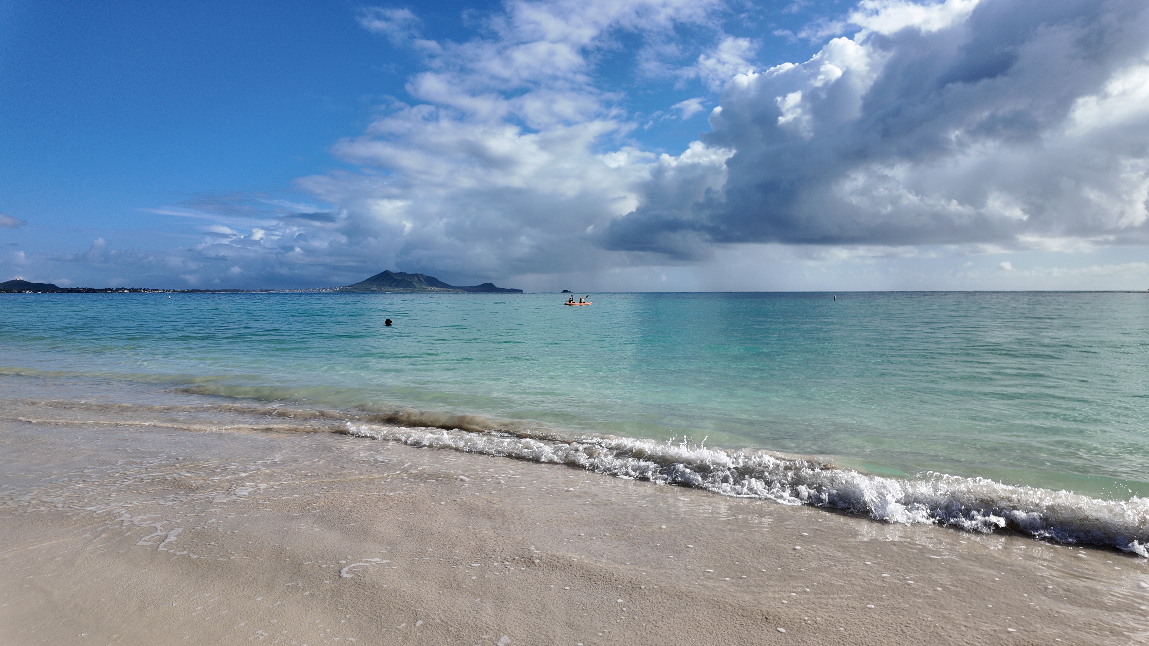 A kayaker in Kailua Bay with mountains in the background.