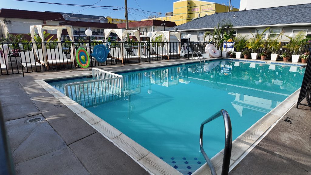 A bright blue hotel pool surrounded by cabanas and tropical trees