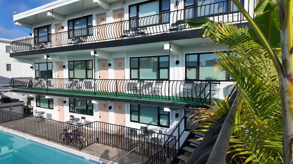 A Wildwood NJ boutique hotel with peach colored doors, tropical plants and an inviting pool