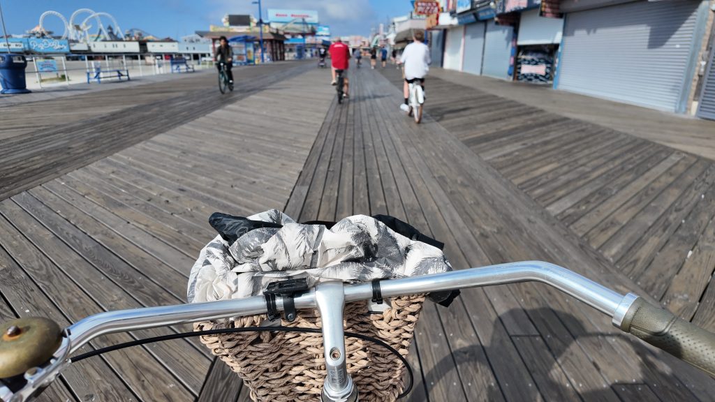 A bike basket with a beach bag in it looking out at a boardwalk in Wildwood NJ