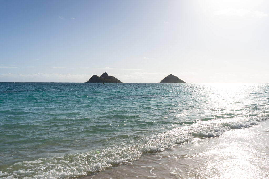 A calm turquoise ocean with two islands in the distance