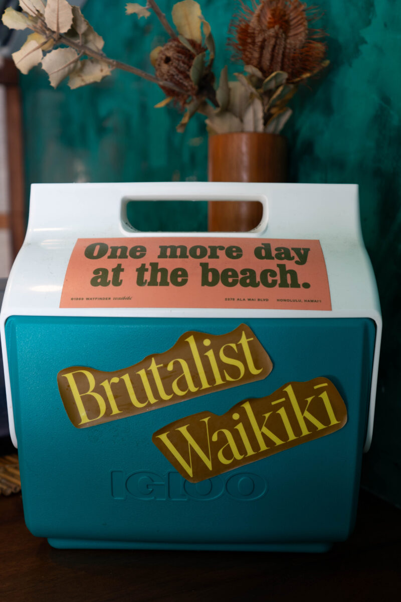 A cooler that has stickers on it saying One more day at the beach and Brutalist Waikiki