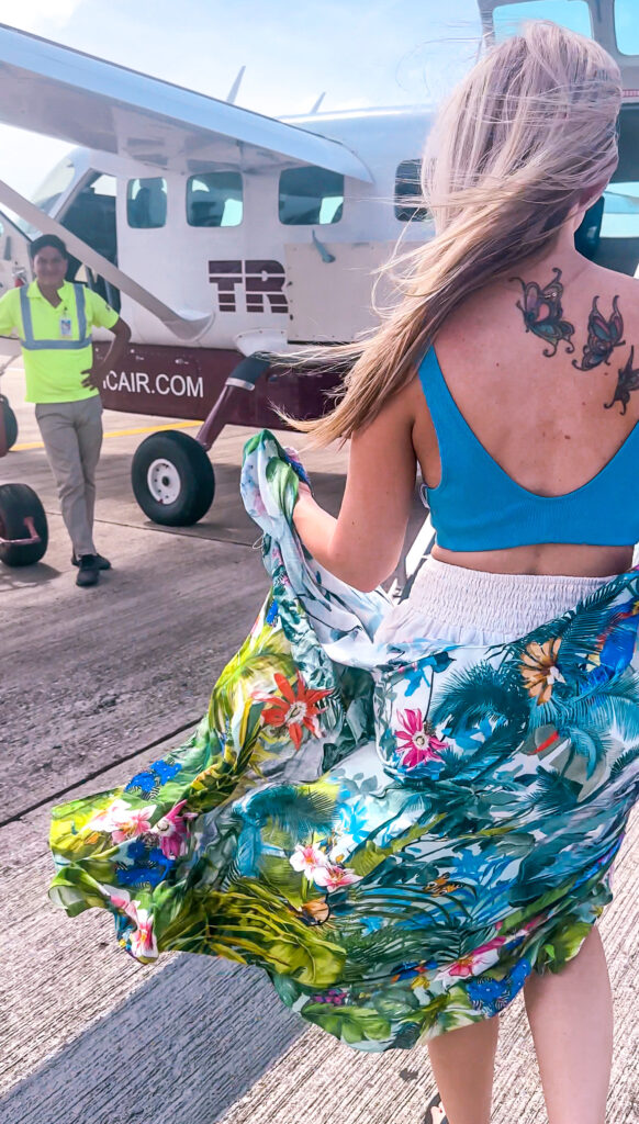 blonde-woman-in-colorful-kimono-boarding-tropic-airplane-during-romantic-caribbean-getaway-in-belize