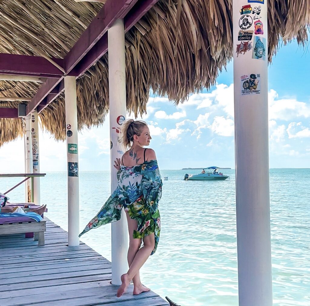 blonde-woman-in-tropical-kimono-standing-on-dock-at-pirates-secret-beach-ambergris-caye-belize