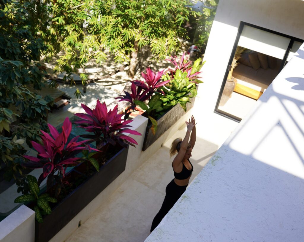 blonde-woman-in-black-doing-yoga-on-deck-above-pool-in-Tulum