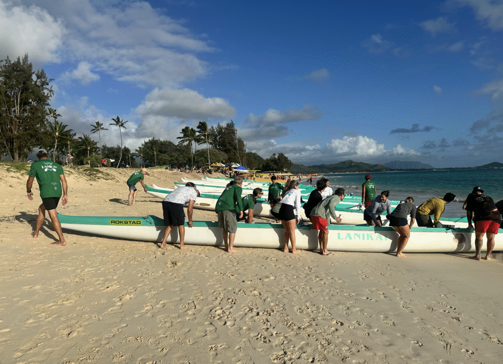 Many outrigger canoes lining Kailua Beach with people bringing them into the water